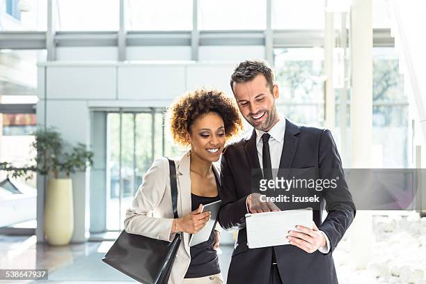 two business people using a digital tablet in an office - hr suit stockfoto's en -beelden
