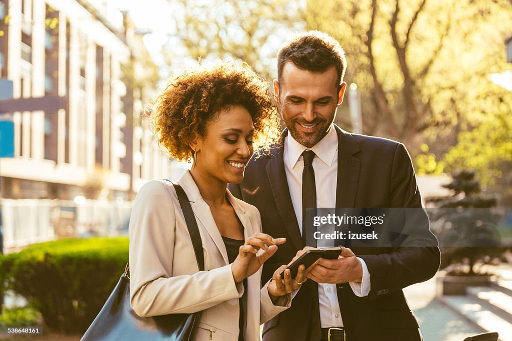 Two business people using smart phones outdoor