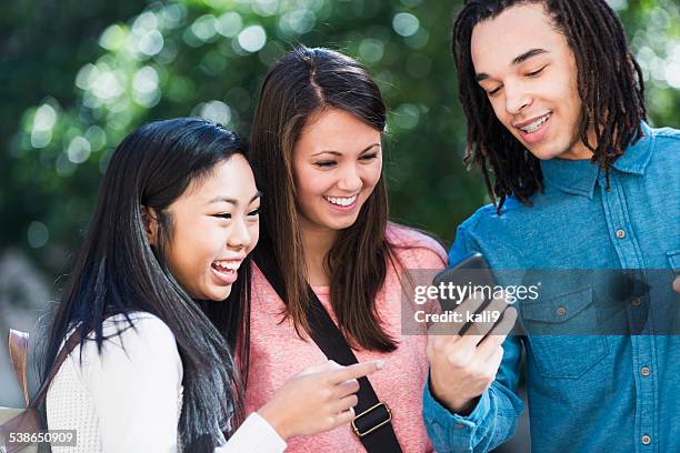 three friends looking at a mobile phone - 3 teenagers mobile outdoors stockfoto's en -beelden