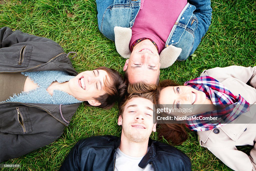 Vier Freunde Leg dich mit dem Rücken auf dem Boden, Lächeln in die Kamera.