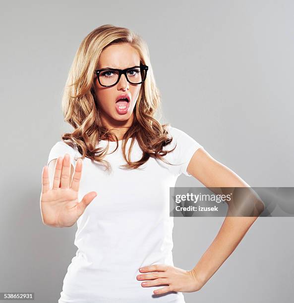 young woman in refusal gesture, studio portrait - word of mouth stock pictures, royalty-free photos & images