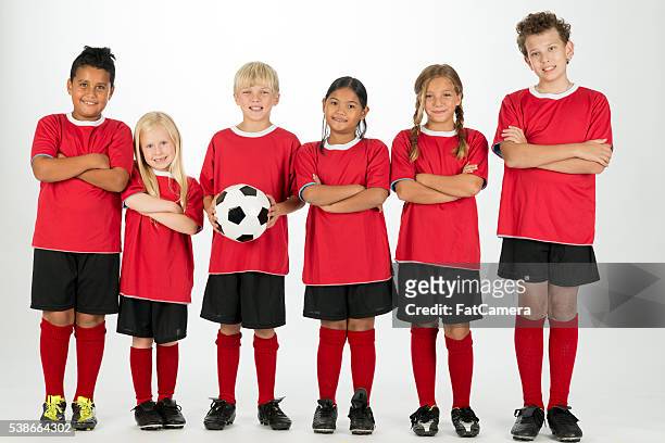 a multi-ethnic group of elementary age children are - red sports jersey stock pictures, royalty-free photos & images