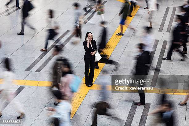 japanese woman talking on the mobile phone surrounded by commuters - incidental people stock pictures, royalty-free photos & images