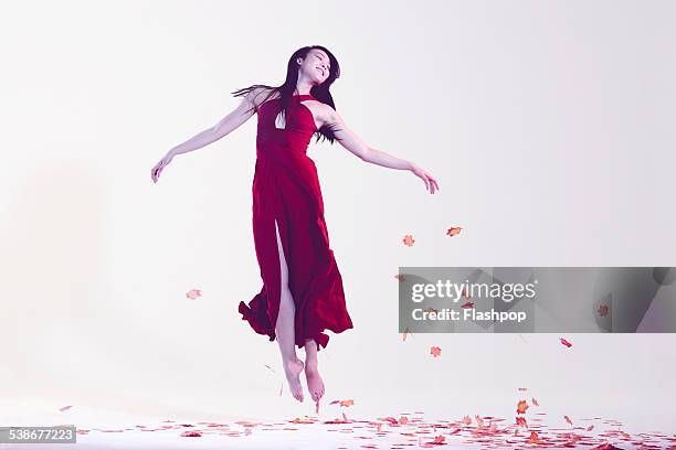 woman jumping amongst leaves - red dress stock pictures, royalty-free photos & images