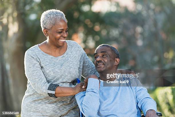 年配のカップルと男性に車椅子 - african american couple walking park ストックフォトと画像