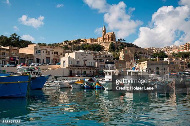 traditional fishing boats in harbor and church - mgarr harbour stock pictures, royalty-free photos & images