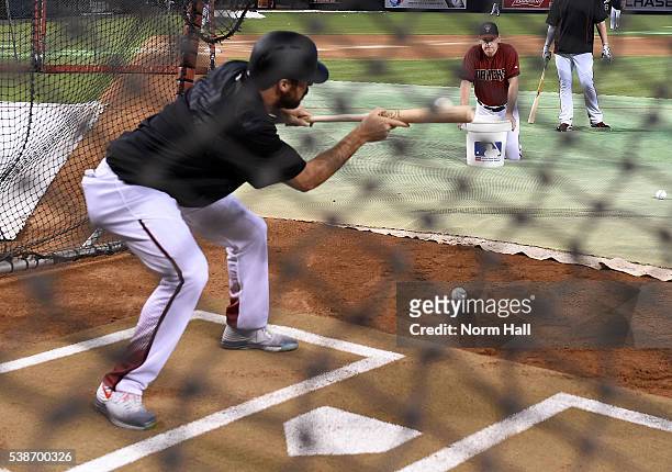 Josh Collmenter of the Arizona Diamondbacks bunts the ball to third base coach Matt Williams during batting practice prior to a game against the...