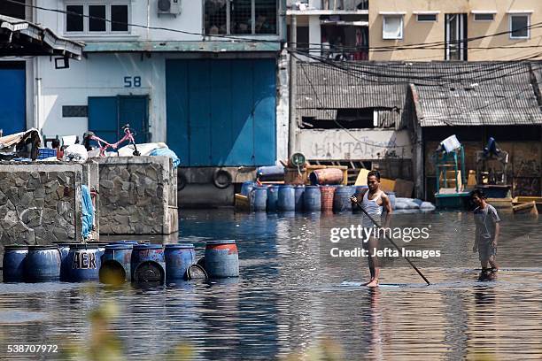 The traffic of vehicles and people passing in the tidal flood inundation in the area of the Port of Muara Baru fish market, on June 7, 2016 in...