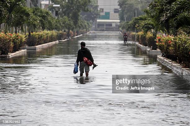 The traffic of vehicles and people passing in the tidal flood inundation in the area of the Port of Muara Baru fish market, on June 7, 2016 in...