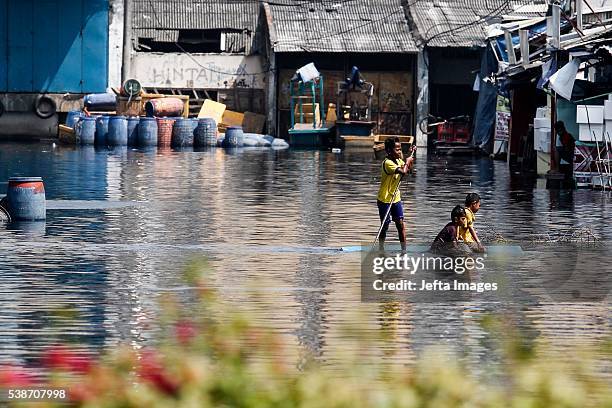 The traffic of vehicles and people passing in the tidal flood inundation in the area of the Port of Muara Baru fish market, on June 7, 2016 in...