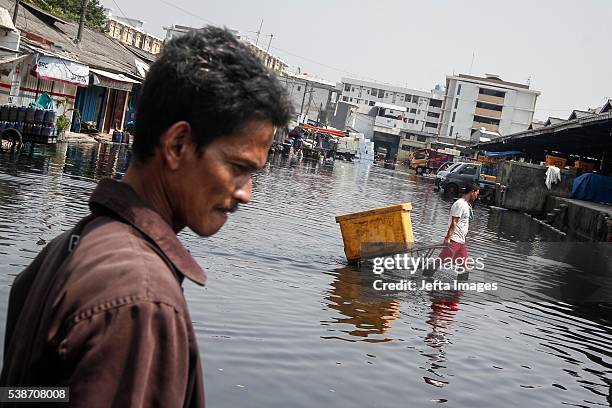 The traffic of vehicles and people passing in the tidal flood inundation in the area of the Port of Muara Baru fish market, on June 7, 2016 in...