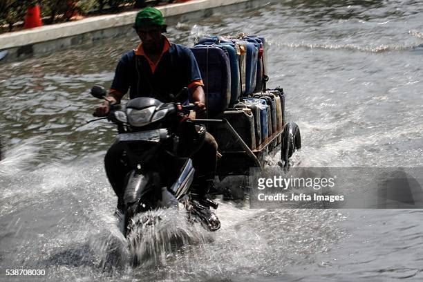 The traffic of vehicles and people passing in the tidal flood inundation in the area of the Port of Muara Baru fish market, on June 7, 2016 in...
