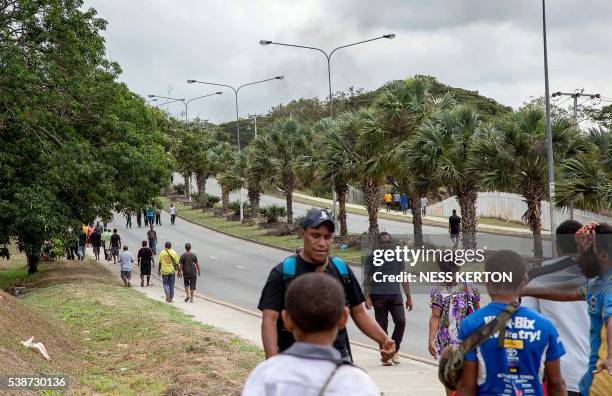 Smoke rises into the area opposite the University of Papua New Guinea as people walk away from the campus following a protest rally by the students...