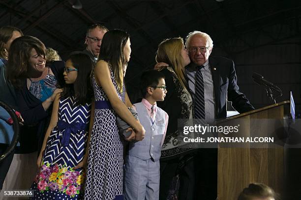 Democratic presidential candidate Senator Bernie Sanders is kissed by his wife Jane on stage with family members during a rally at Barker Hangar in...