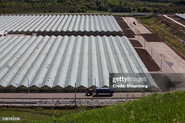 Farm worker drives a tractor and trailer past Soviet era hothouses used to grow vegetables at the Yuzhny Agricultural Complex, operated by AFK...