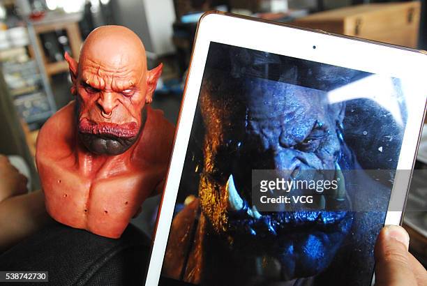 Artist Yan Chuan compares his collection figurine creation of Garrosh Hellscream from World of Warcraft with an image of Hellscream on June 8, 2016...