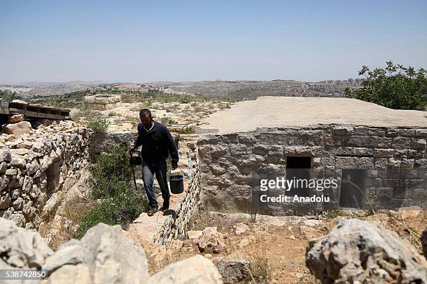 Palestinian Muhanned Salah carries a bucket filled with water in the Sushahle village, which is surrounded by Jewish settlements, in Bethlehem, West...