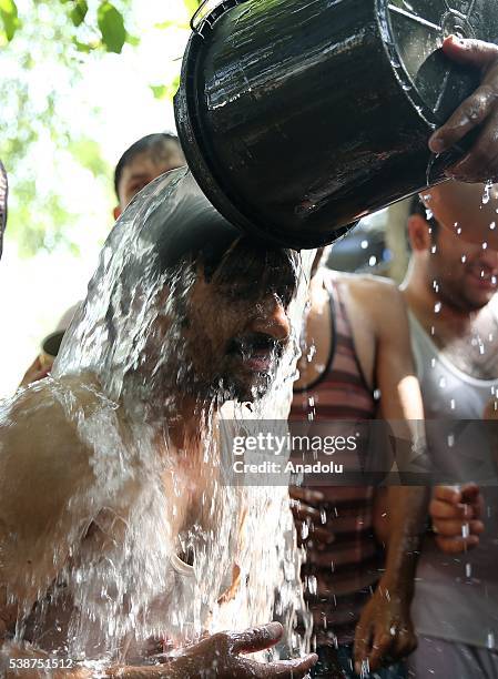 Pakistani man pours water over another man's head as they cool off to beat the heat during the Islamic holy fasting month of Ramadan, in Islamabad,...