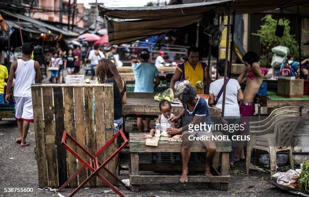 Women feeds her grandson in Divisoria Market in Manila on June 8, 2016. The Philippines' economy grew a better-than-expected 6.9 percent in the first...