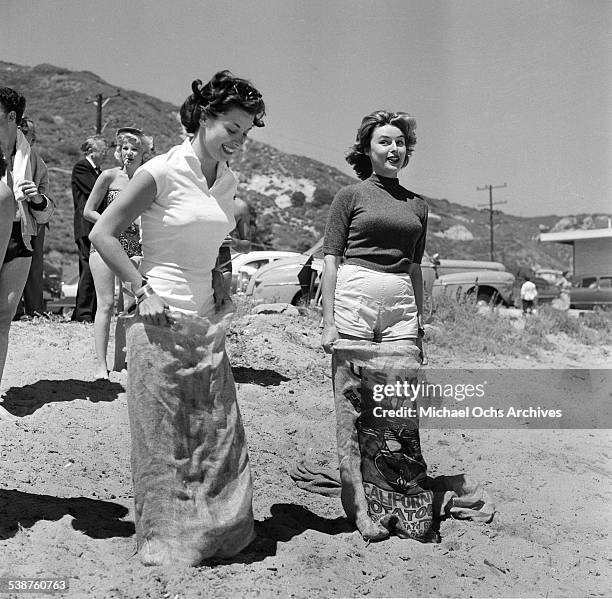 Actress Elaine Stewart and Adelle August enter a sack race during the Thalians Beach Ball in Malibu,California.