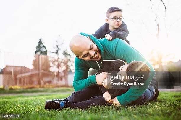 dad playing outside with his boys - play fight stock pictures, royalty-free photos & images