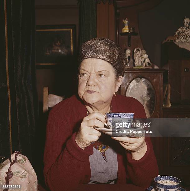 English actress Violet Carson who plays the character of Ena Sharples in the television soap opera Coronation Street, drinks a cup of tea at home in...