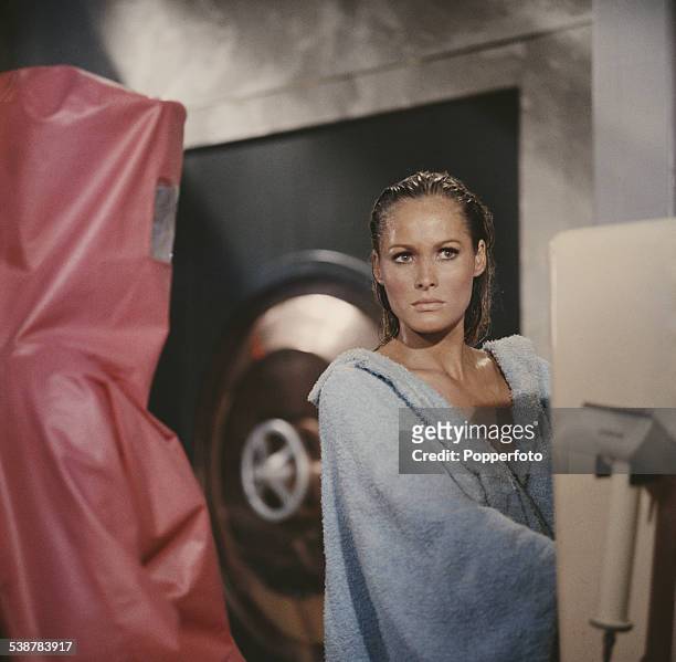 Swiss born actress Ursula Andress pictured in character as Honey Ryder, wearing a blue robe in a scene from the James Bond film Dr. No at Pinewood...