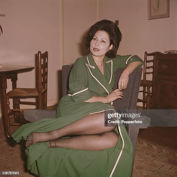 Israeli actress Haya Harareet pictured wearing a green gown in a living room in 1962.