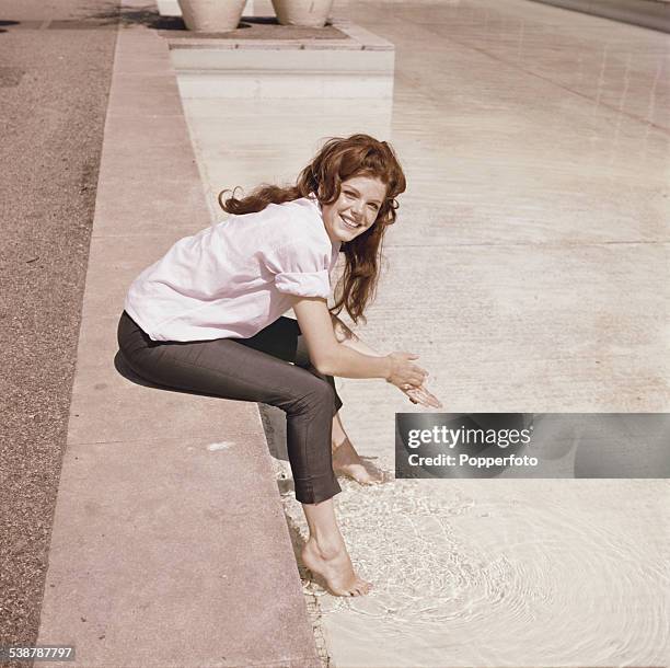 English actress Samantha Eggar, who appears in the film 'The Wild and the Willing', pictured sitting on a stone wall next to a pool of water in 1962.