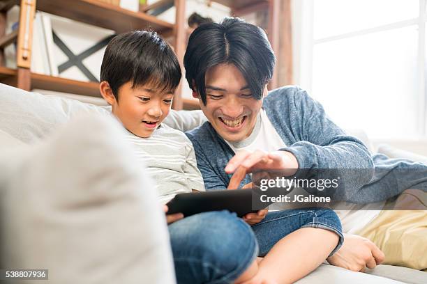 father and son playing with a digital tablet together - using digital tablet asian stock pictures, royalty-free photos & images