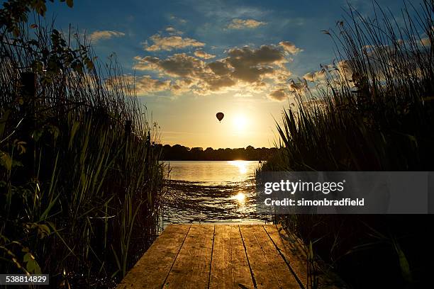 hot air balloon drifting over lake - frensham stock pictures, royalty-free photos & images