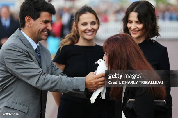 Mayor of Cabourg Tristan Duval, French actresses Virginie Ledoyen, Juliette Binoche and actress Ariane Ascaride hold a dove on June 8, 2016 for the...