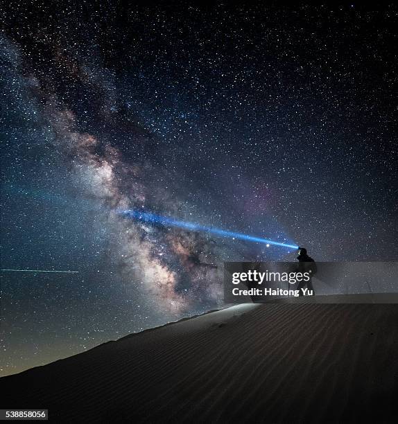 man standing on sand dune with headlamp on and milky way as backdrop - lampe de poche photos et images de collection