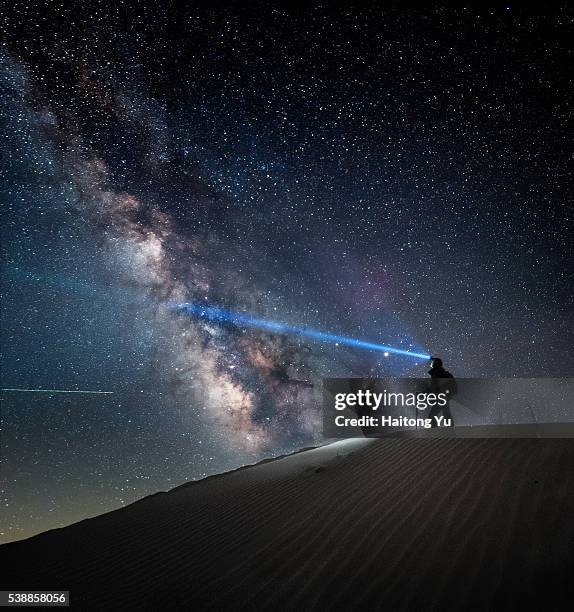 man standing on sand dune with headlamp on and milky way as backdrop - inner mongolia photos et images de collection