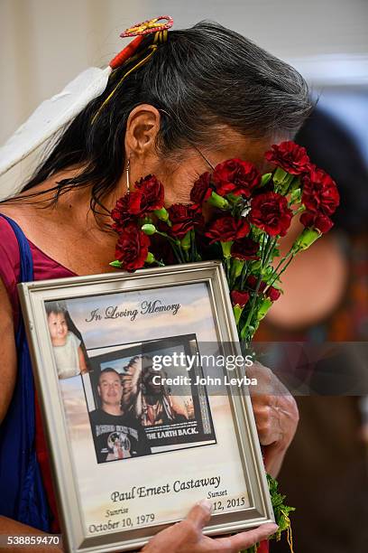 Lynn Eagle Feather weeps as she buries her face in a bouquet of carnations while holding a sign in memory for her son Paul Ernest Castaway who was...