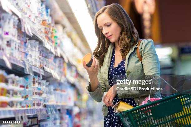 mulher a ler na loja de mercearia rótulos de alimentos - iogurte imagens e fotografias de stock