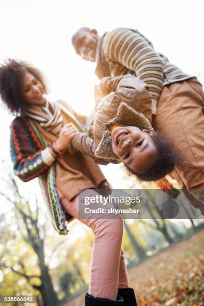 happy african american little girl having fun with parents outdoors. - holding upside down stock pictures, royalty-free photos & images