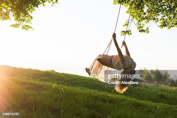 young woman having fun swinging in sunlight - woman on swing stock pictures, royalty-free photos & images