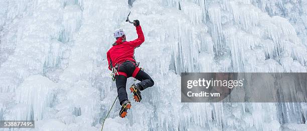 ice climber ascending a frozen waterfall - ice climbing stock pictures, royalty-free photos & images