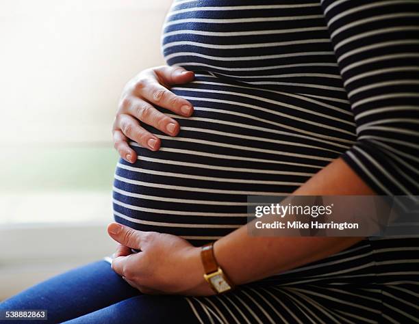 heavily pregnant woman holding her bump - embarazada fotos fotografías e imágenes de stock