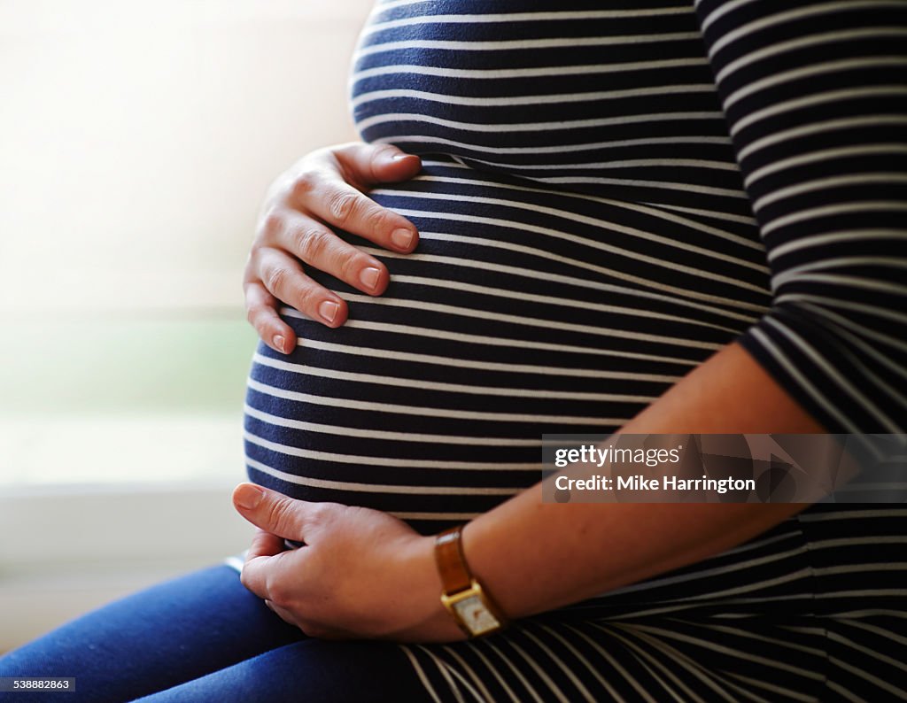 Heavily pregnant woman holding her bump