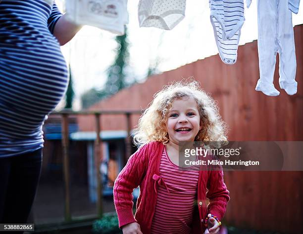 girl playing in garden while mother hangs washing - red dress child stock pictures, royalty-free photos & images