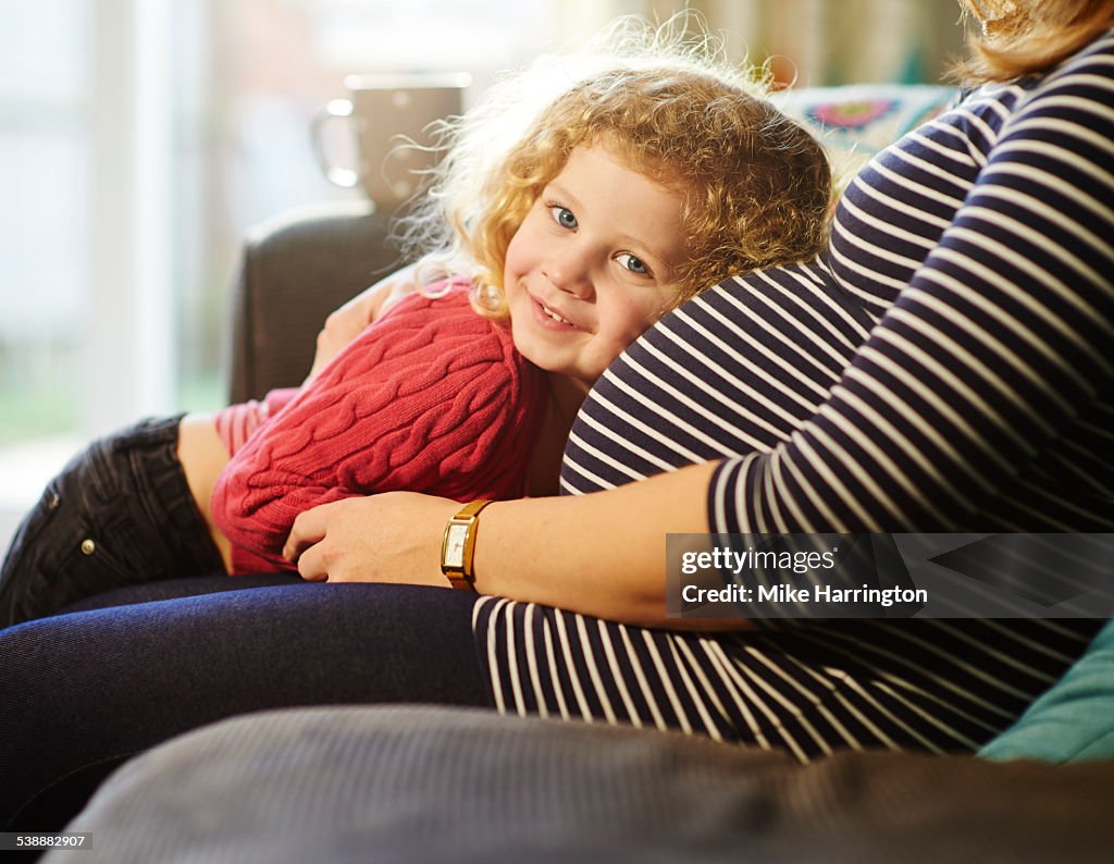 Daughter laying on pregnant mothers bump