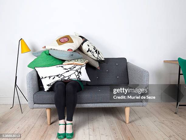 woman sitting under pile of pillows - hide stock-fotos und bilder