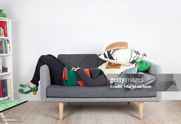 woman hidden by pillows - bookshelf foto e immagini stock
