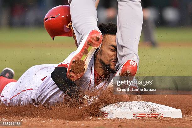Billy Hamilton of the Cincinnati Reds slides into the legs of Jhonny Peralta of the St. Louis Cardinals while trying to steal third base in the fifth...