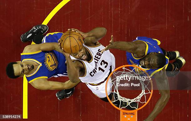 Tristan Thompson of the Cleveland Cavaliers drives to the basket against Draymond Green of the Golden State Warriors and Shaun Livingston during the...