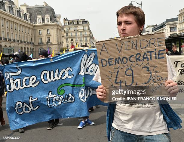 Protestor carries a placard reading, "For sale, Democracy, only 49,3 euros" during a demonstration against the French government's labour law reforms...