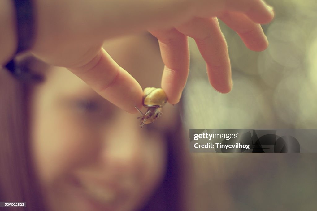 Young girl holding a snail between fingers