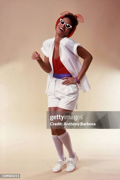 Portrait of model Sheila Johnson as she poses in summer fashion, New York, 1970s. She wears a red shirt under a white shirt, white shorts, socks and...